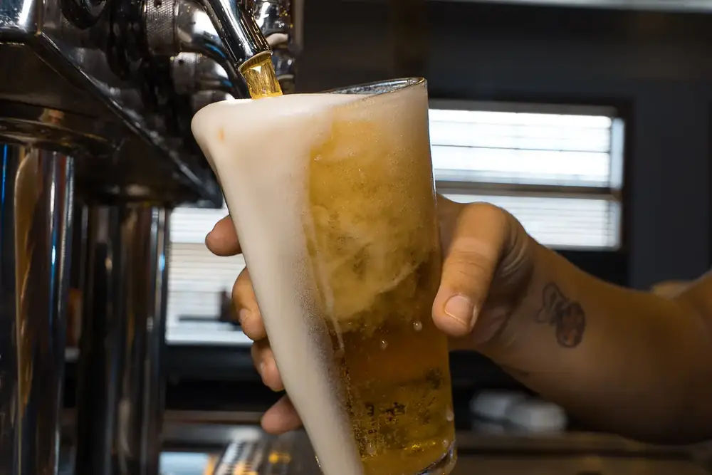 A cold draft beer being poured from the tap at 212