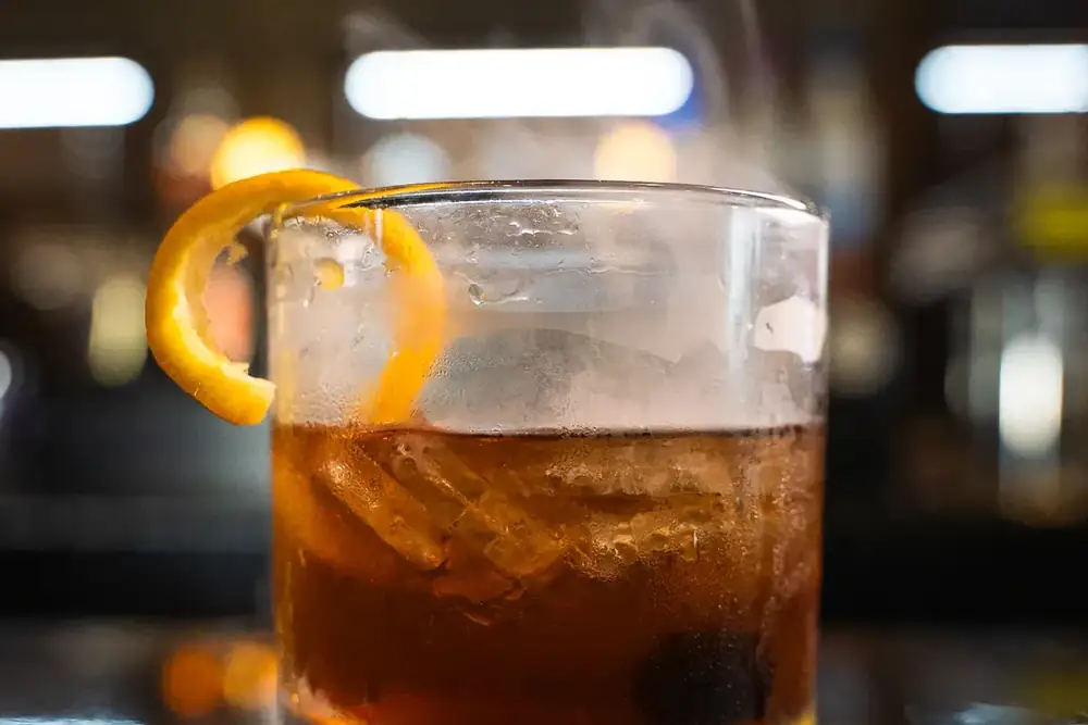 A smoked old fashioned with an orange twist on the bar at 212