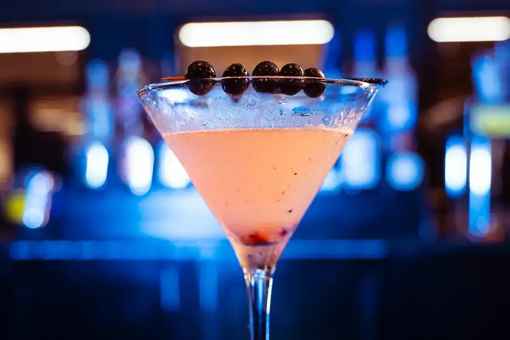 A pink cosmopolitan martini glowing under the bar lights at 212