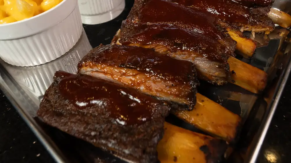 A rack of house smoked ribs with mac and cheese and baked beans on a tray at 212