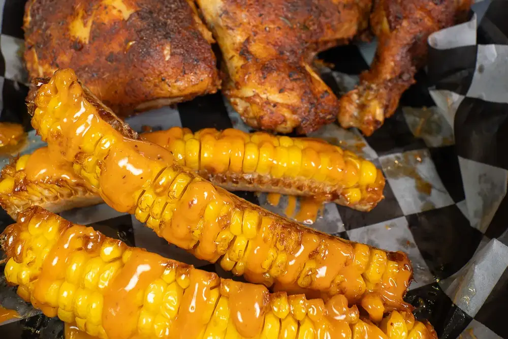 Smoked chicken with corn ribs in a paper-lined basket at 212