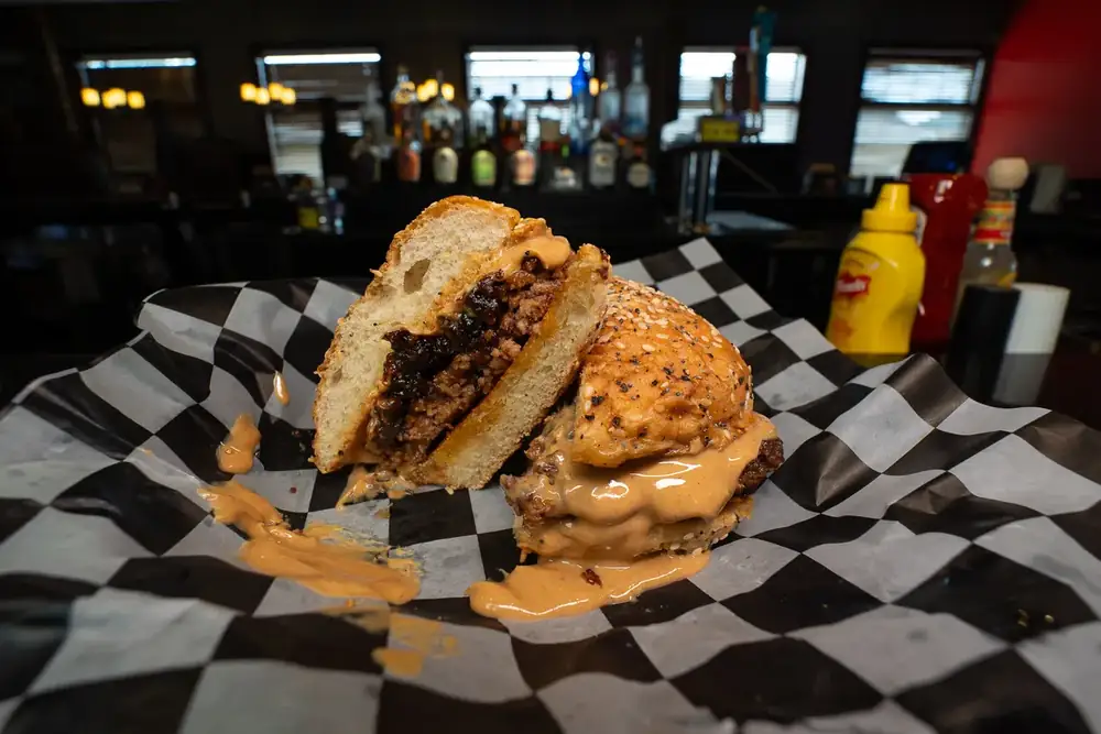 A burger cut in half to show the bacon jam and peanut butter, on checkered paper at 212