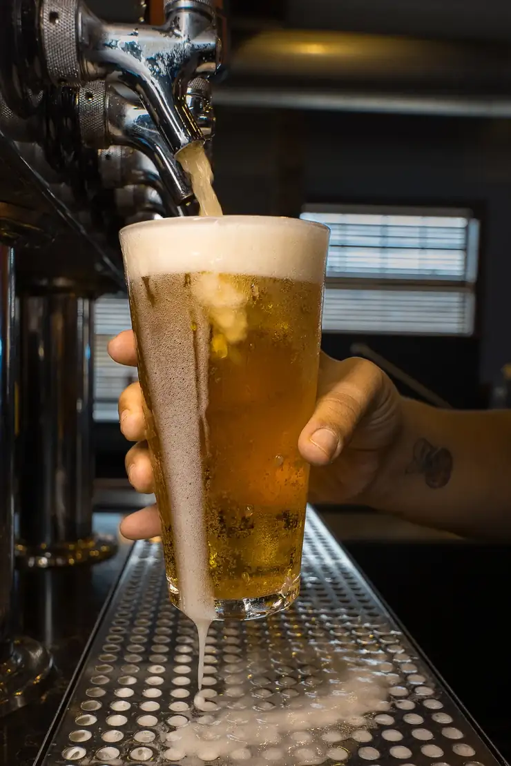 A cold draft beer being poured behind the bar at 212