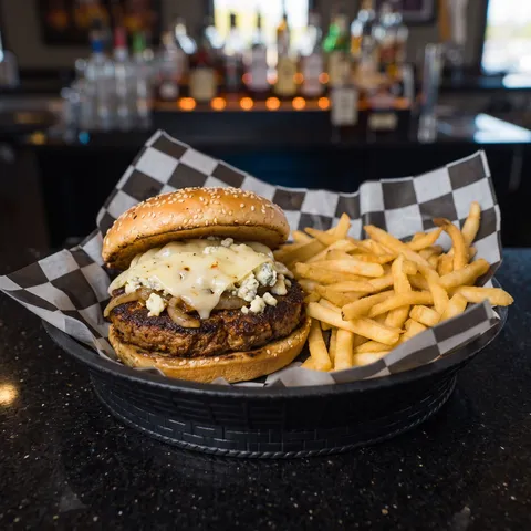 The Cajun Bleu burger with sauteed onions, bleu cheese crumbles and melted pepper jack on a sesame bun, served with fries