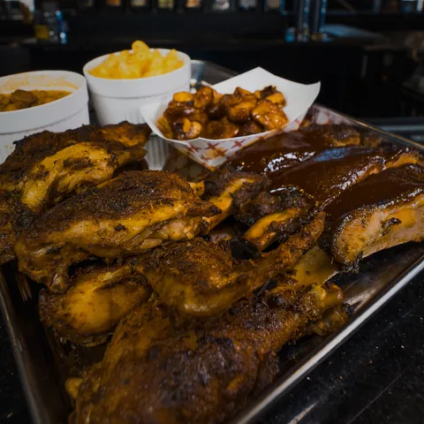 A meat combo tray of smoked chicken, ribs and burnt ends with three sides