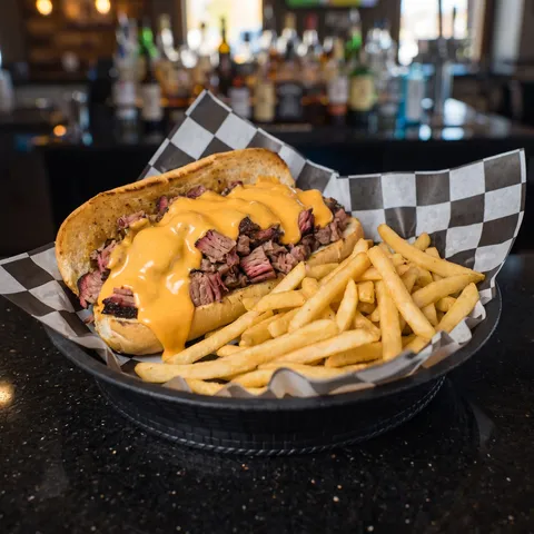 Chopped smoked brisket smothered in cheddar cheese sauce on a toasted hoagie, served with fries